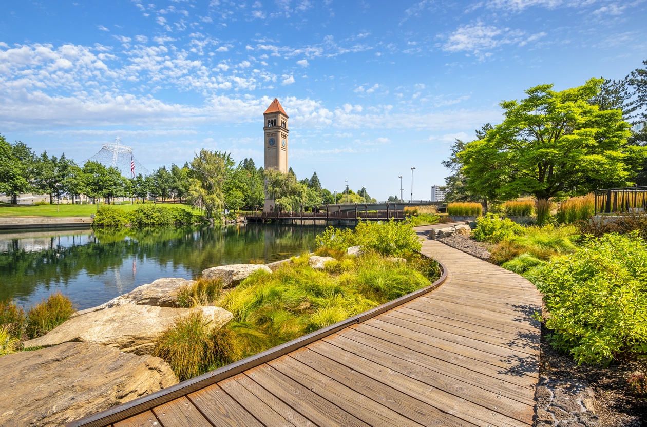 View from the Spokane River waterfront promenade path looking towards the pavilion and clock tower at the public Riverfront Park in downtown Spokane, Washington, USA.